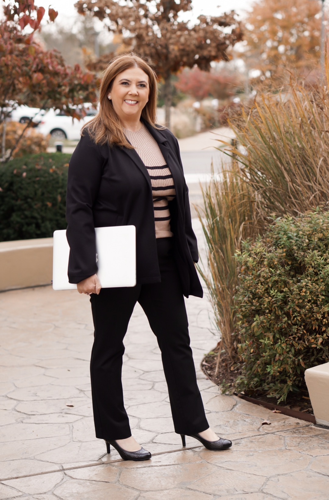 Ginger Steg in a blazer holding a laptop, professional and approachable