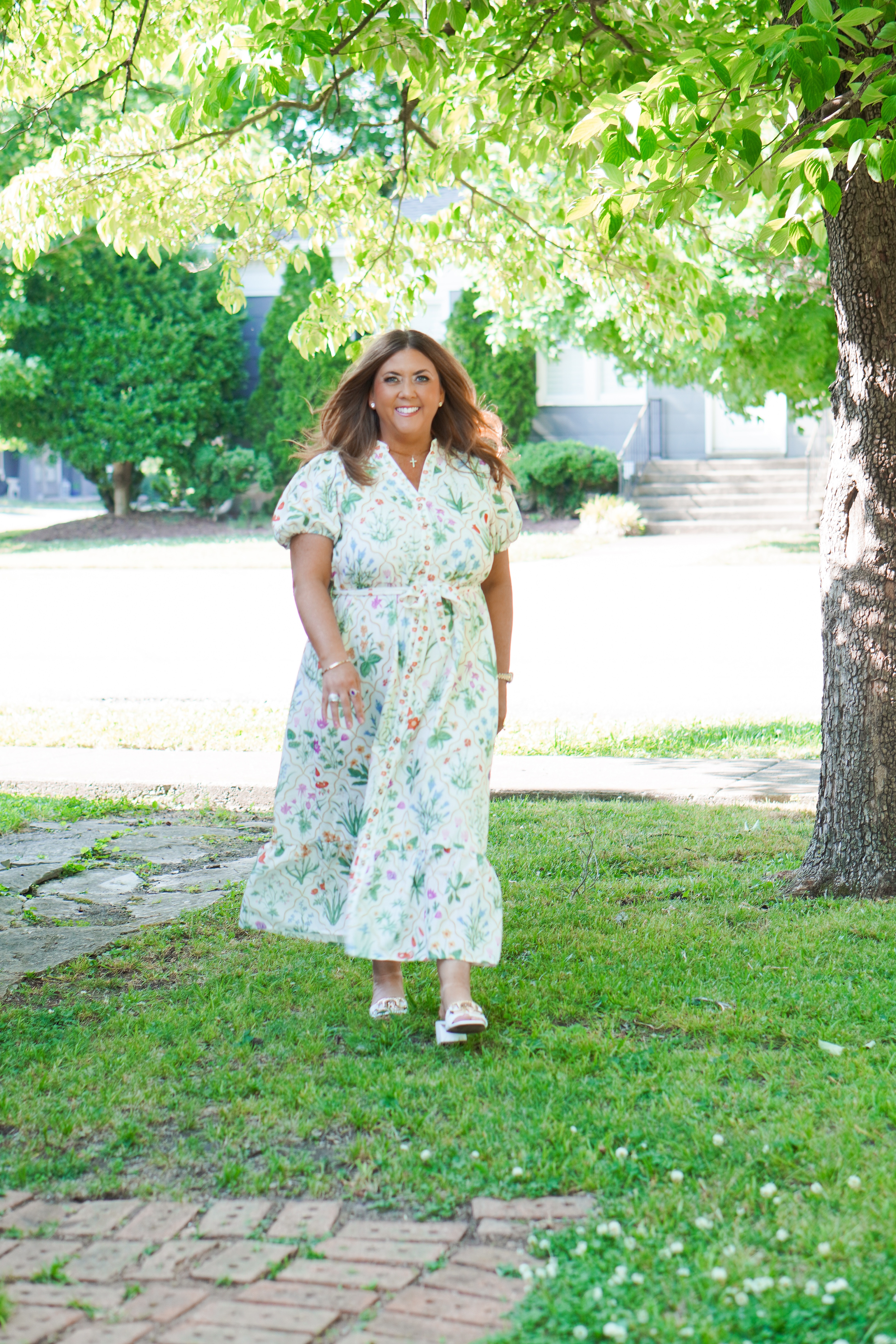 Ginger Steg standing outdoors in a floral dress under a shade tree